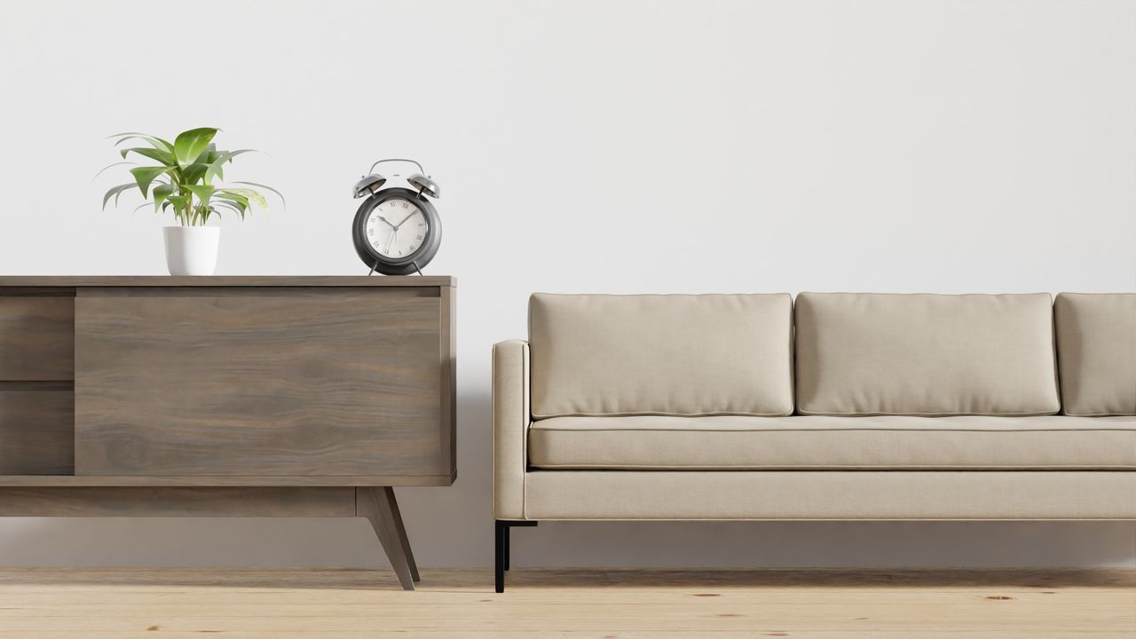 Services Modern minimalist living room featuring a beige couch, wooden cabinet, and a potted plant.