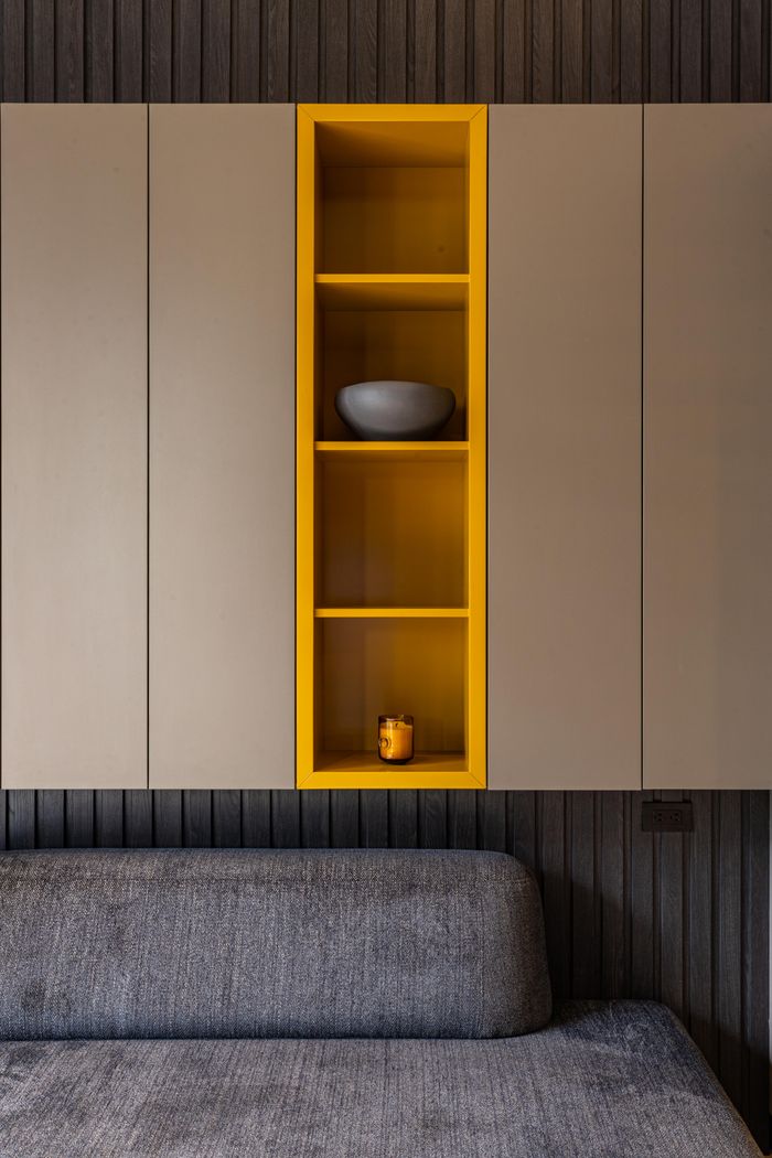 Services Modern living room featuring minimalist shelves, a sofa, and a striking yellow accent design.