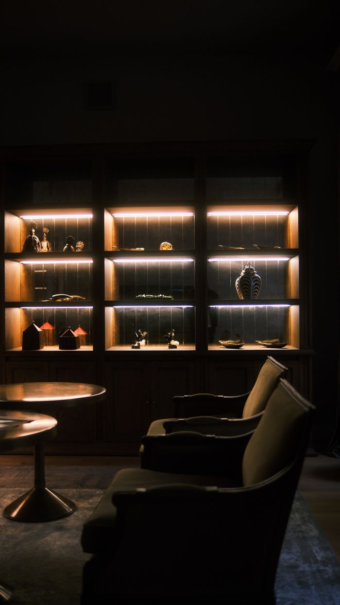 Services Warmly lit shelves with elegant decor create a cozy ambiance in a dimly lit room.