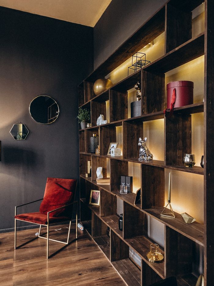 About Stylish modern interior with illuminated wooden shelves and a red chair.
